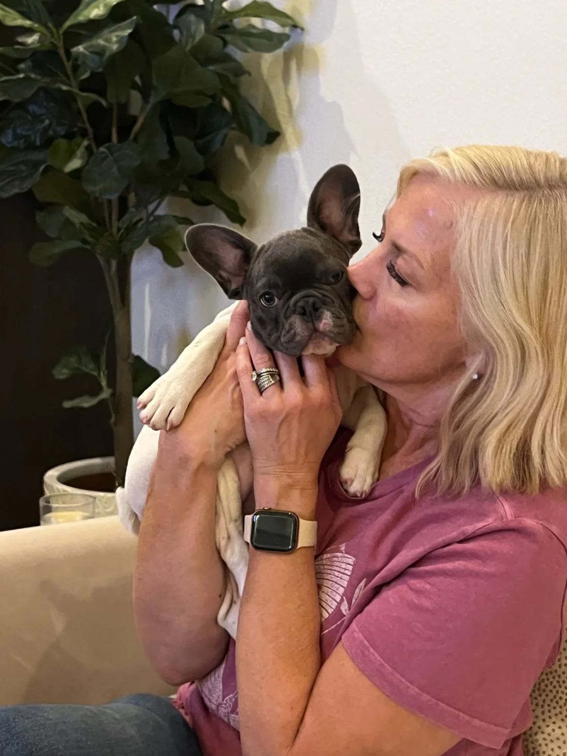 Woman kissing a black and tan French Bulldog puppy